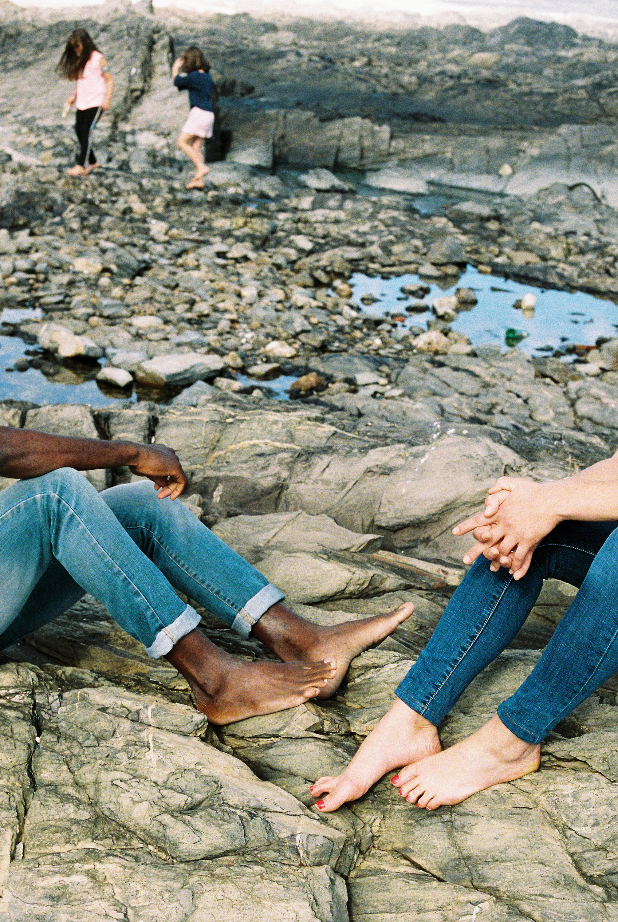 Cropped photo of two people sitting on a rocky beach